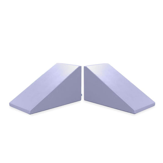 Two Foamnasium Mega Wedge Play Triangles, featuring a purple CertiPUR-US certified foam construction, are positioned side by side with their sloped sides facing each other. These wedges have one side higher than the other and are commonly used in gymnastics, physical therapy, or exercise for balance and support.