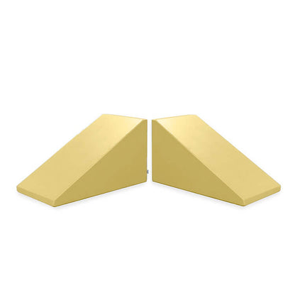 Two identical, light-yellow triangular wedge-shaped objects positioned side by side, mirroring each other with their slanted surfaces facing outward. The Mega Wedge Play Triangles by Foamnasium are a durable foam playset featuring straight edges and a flat base, ensuring both fun and safety for children during playtime.