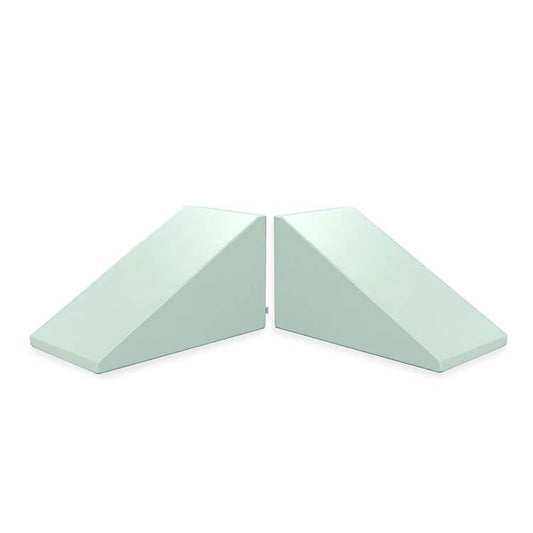 Two light blue foam wedge-shaped cushions, known as Mega Wedge Play Triangles by Foamnasium, are situated side by side against a white background. Each wedge is identical in size and shape, with one oriented to the left and the other to the right. These cushions are CertiPUR-US certified.