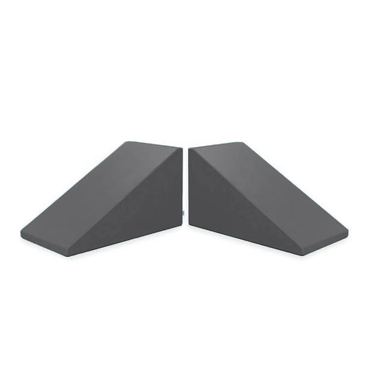 Image of two dark gray Mega Wedge Play Triangles from Foamnasium, positioned side by side. The wedges have a sloped design for sliding under doors to keep them open or secure, crafted from durable foam playset materials and GREENGUARD GOLD Certified for safety.